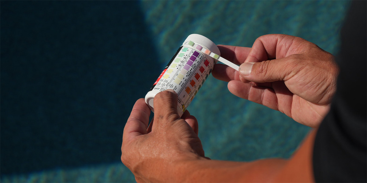 Pool service employee testing the pH levels in a swimming pool